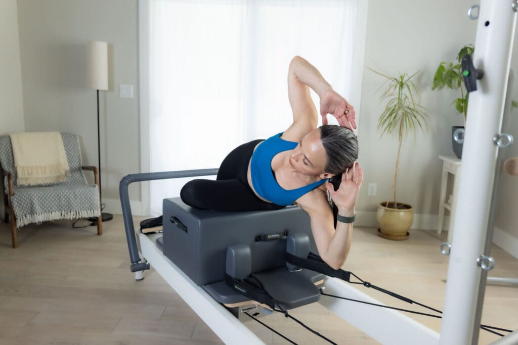 Woman in a Pilates studio working on a reformer.