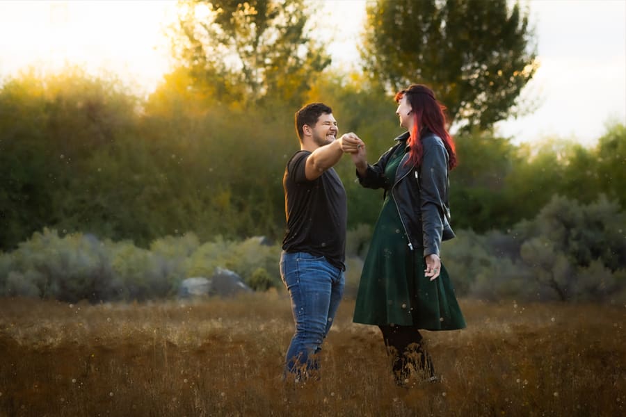 Man and woman couple dancing in a fall colored field for couples photos.