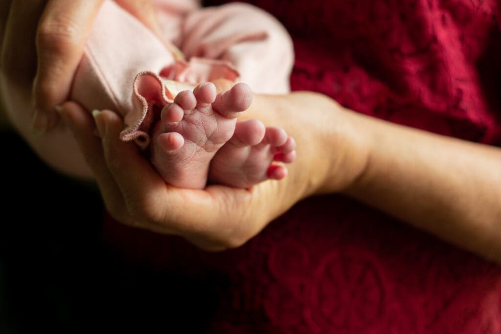 Hand holding newborn baby feet.