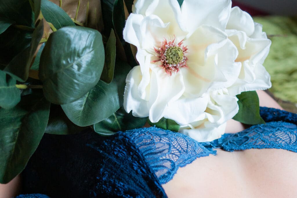 White flowers laying on a woman's chest with a blue bra.